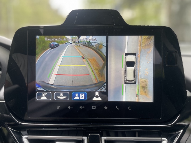 Suzuki S-Cross Hybrid 4x4 mit Schaltgetriebe: Zwei geteiltes Bild der Kamera. Aus der Vogelperspektive und Frontkamera oder Heckkamera. Gesplittet auf dem Touchscreen